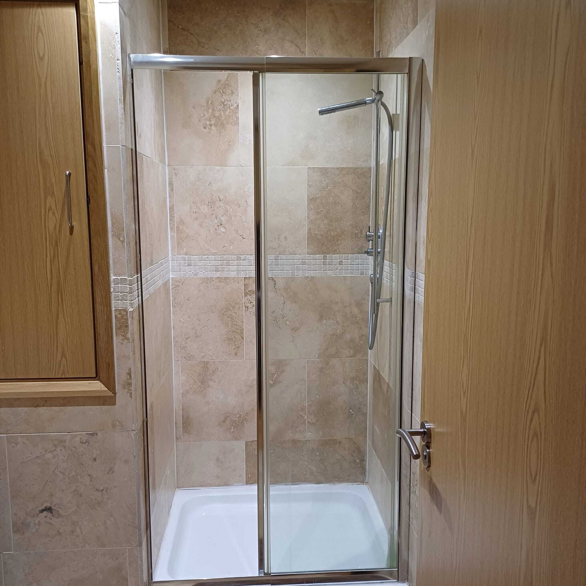Een douche met glazen wand en een witte badkuip.