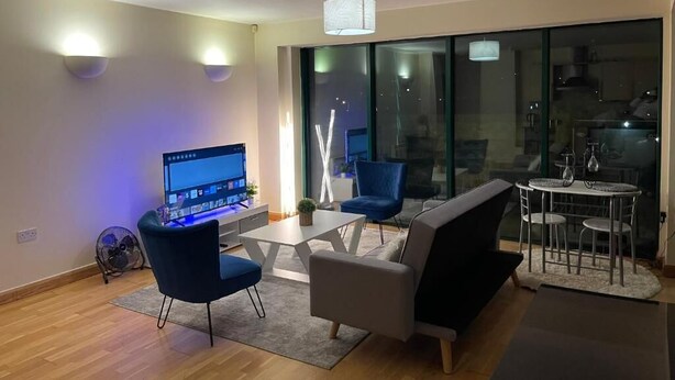 Un salon moderne comprenant un bureau, deux fauteuils, un canapé et une table à manger.