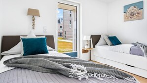A modern bedroom with a bed, a sofa, a door leading to an outdoor area, and a painting on the wall. - Lovely apartment in Olpenitz with sauna (Olpenitz)