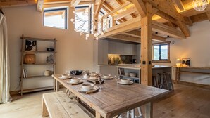 A rustic wooden dining table set with plates, bowls, and glasses, surrounded by wooden beams and a high ceiling. - MAISON ORIGINE - BEAUFORT (BEAUFORT)