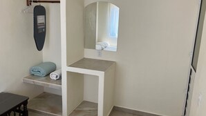 A compact bathroom with a towel rack, a mirror, and a small shelf with a folded towel. - Los Amores Apartments C (Perula)