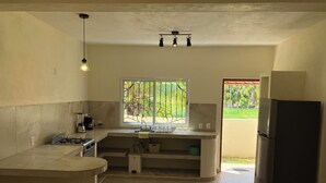 A kitchen with a central island, a refrigerator, and a window with a view of greenery. - Los Amores Apartments C (Perula)