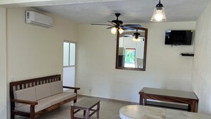 A living room with a sofa, a coffee table, a TV, and a ceiling fan. - Los Amores Apartments C (Perula)