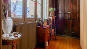Un couloir doté d’un plancher en bois, de grandes fenêtres, d’un radiateur et d’une porte.