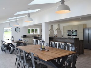 Una cocina moderna con una isla central, luces colgantes y un comedor con sillas y una mesa.