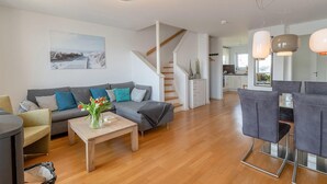 A modern living room with a sofa, coffee table, and a staircase leading to a kitchen.