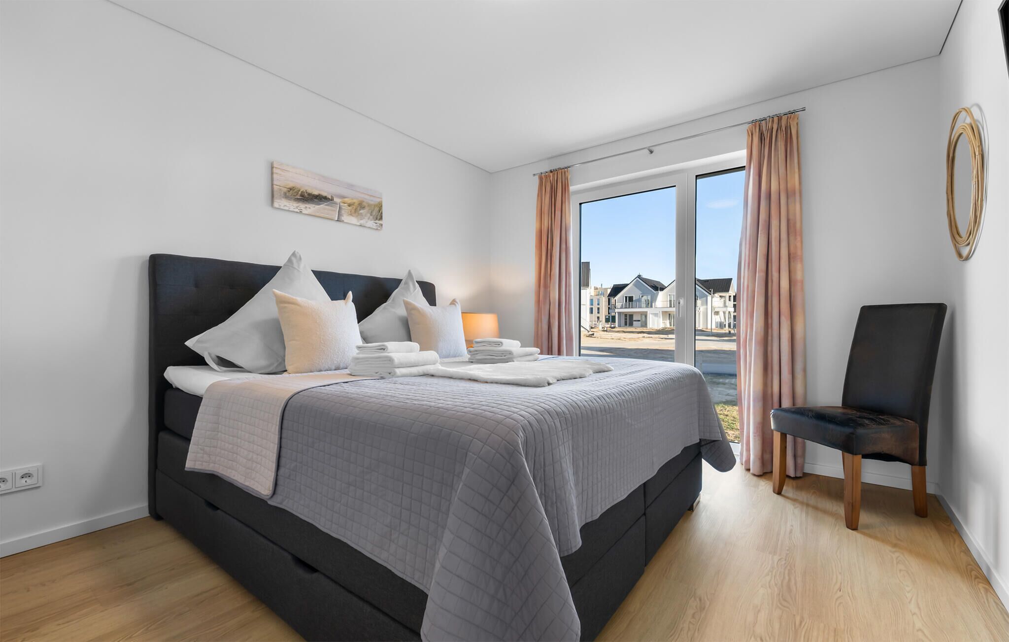 A modern bedroom with a large bed, a chair, and a view of the outside.
