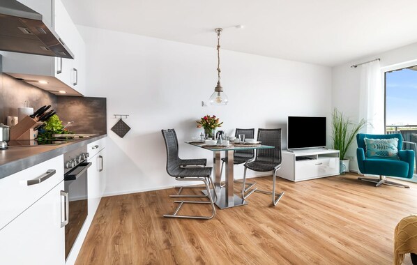 A modern kitchen with a dining area, a TV, and a balcony with a view. - 2 bedroom lovely apartment in Olpenitz (Olpenitz)
