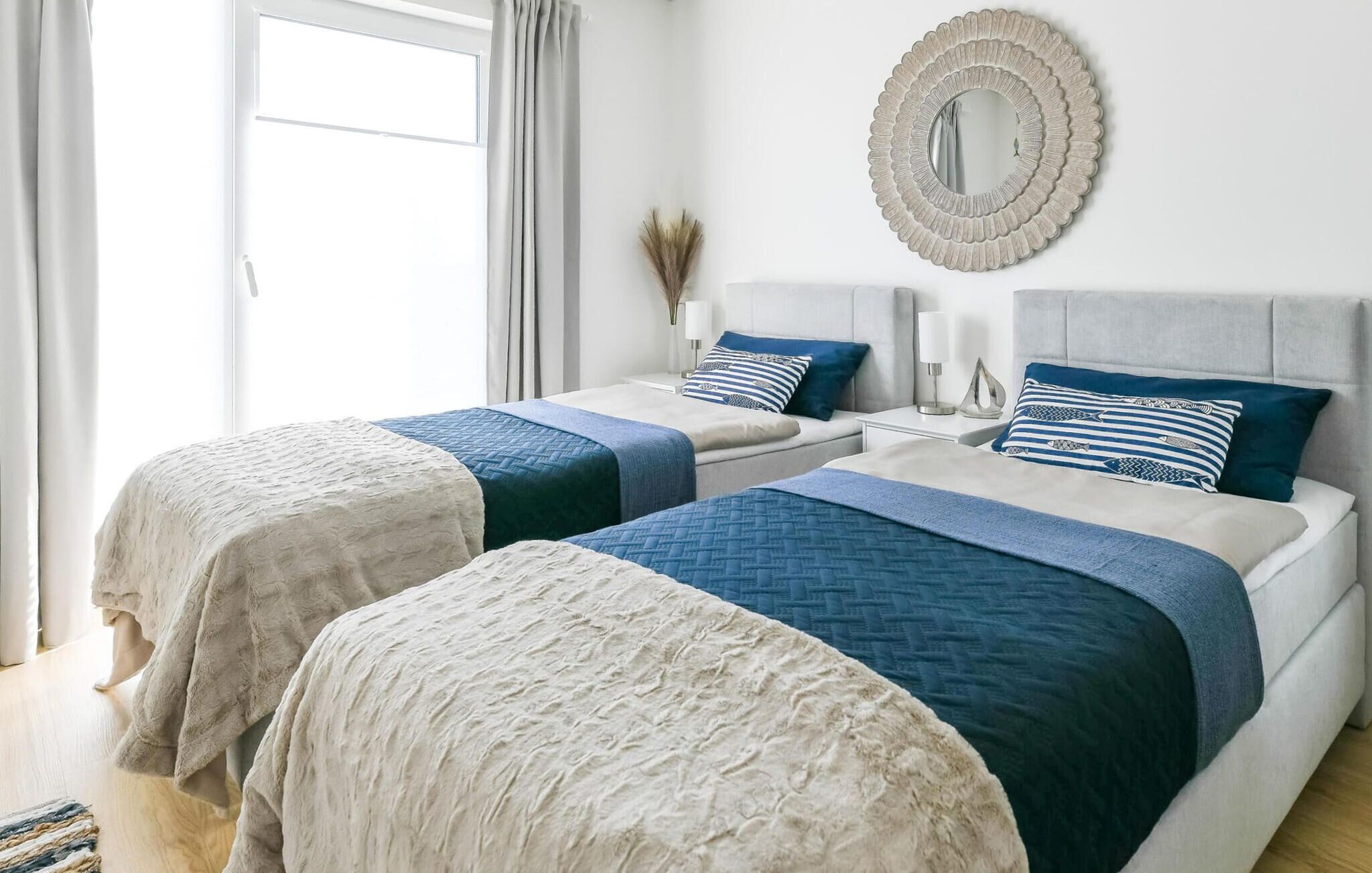A bedroom with two beds, each with a headboard, and a large mirror on the wall.