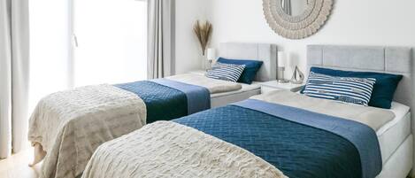 A bedroom with two beds, each with a headboard, and a large mirror on the wall.
