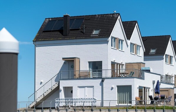 A two-story building with a balcony, a staircase, and a small outdoor seating area.
