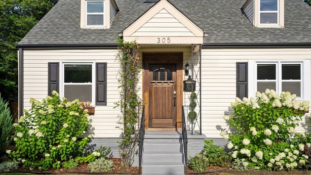 A two-story house with a number 305 on the front door, a small porch, and a well-maintained front yard with shrubs. - 1 Mile to DT, King Bed, Fenced Yard, Fire Pit, Pet Friendly (Raleigh)