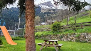 A playground with a slide and climbing structure, a picnic table, and a stone wall. - LE GENEPI - LES BELLEVILLE (LES BELLEVILLE)