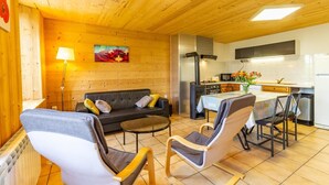 A cozy wooden interior with a sofa, chairs, a dining table, and a kitchen area. - LE GENEPI - LES BELLEVILLE (LES BELLEVILLE)