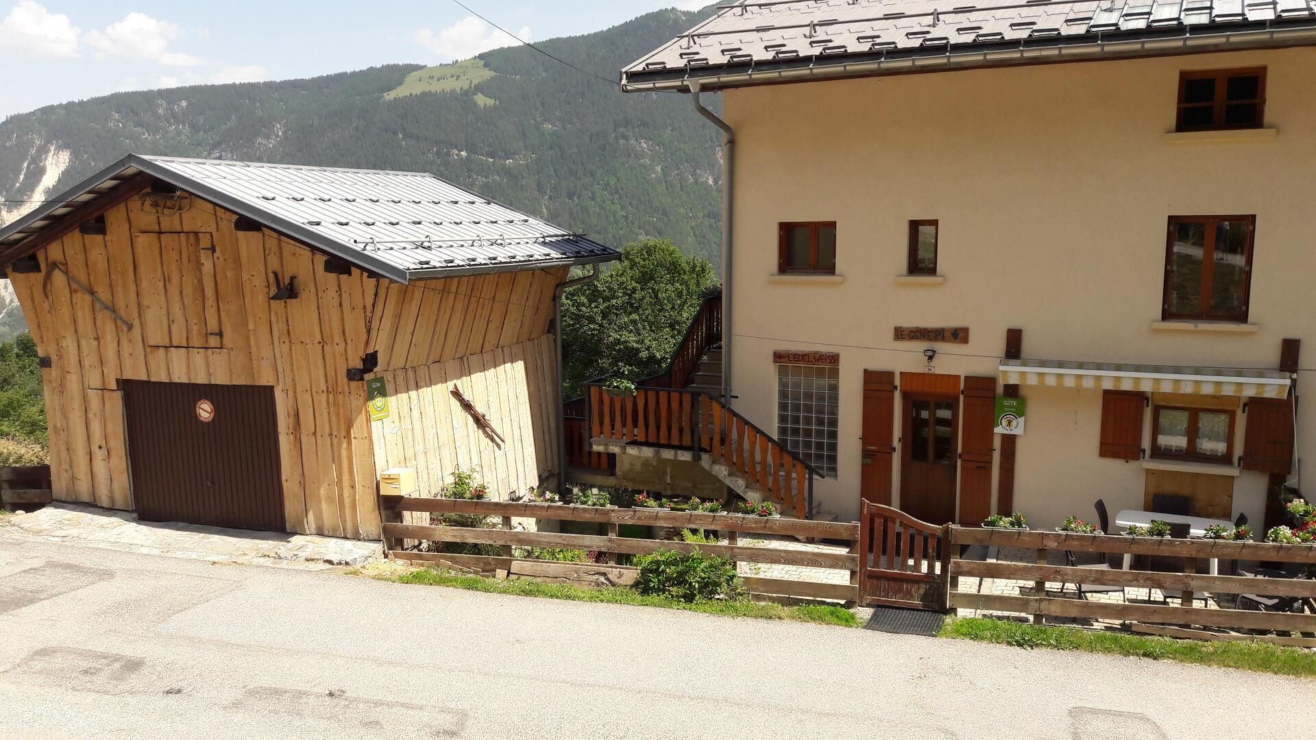 A wooden building with a metal roof, a staircase leading to a door, and a small outdoor seating area with a table and chairs.