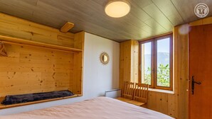 A wooden cabin room with a bed, a window with a view, and a door. - LE GENEPI - LES BELLEVILLE (LES BELLEVILLE)