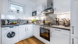Eine moderne Küche mit weißen Schränken, einer Bosch Waschmaschine, einem Bosch Backofen und einer Kaffeemaschine.