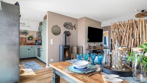 A modern kitchen with teal cabinets, a built-in stove, and a dining area with a wooden table set for four. - Gorgeous apartment in Olpenitz (Olpenitz)