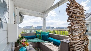 A covered outdoor seating area with a view of houses and a lighthouse in the distance. - Gorgeous apartment in Olpenitz (Olpenitz)