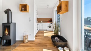 Une cuisine moderne équipée d’un lave-linge encastré, d’une étagère en bois et d’un coin salon confortable avec un panier pour chien.