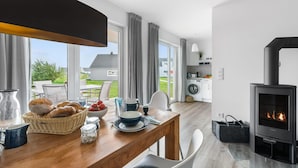 Une cuisine moderne dotée d’une cuisinière intégrée, d’un coin repas avec une table en bois et d’une vue sur l’extérieur.