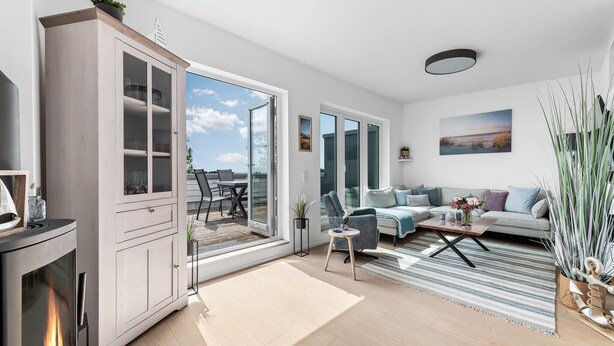 Un salon moderne doté d’une cheminée, d’un ensemble de canapés, d’un coin repas avec des chaises et d’une vue sur l’extérieur grâce à de grandes portes vitrées.