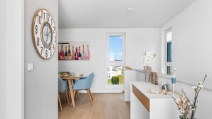 Une cuisine moderne avec un coin repas, un plancher en bois et une grande horloge au mur.
