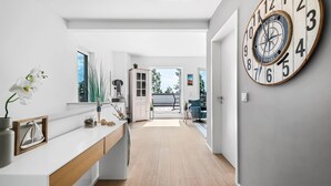 Une cuisine moderne avec un plan de travail en bois, une grande horloge au mur et une vue sur l’extérieur.
