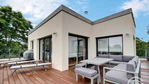 A modern outdoor deck with a dining area, a barbecue grill, and a sofa. - Le Menhir - PLEUMEUR BODOU (PLEUMEUR BODOU)