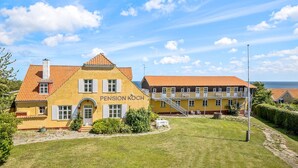 Un bâtiment jaune avec un toit rouge et l’inscription « Pension Koch » sur la façade.