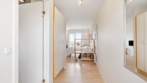 Un couloir comprenant un lit, une petite table et un miroir.