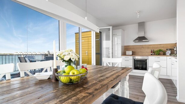A modern kitchen with white cabinets, a wooden countertop, and a stainless steel range hood.