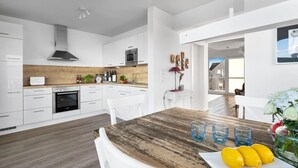 A modern kitchen with white cabinetry, a wooden countertop, and a dining area with a rustic table.