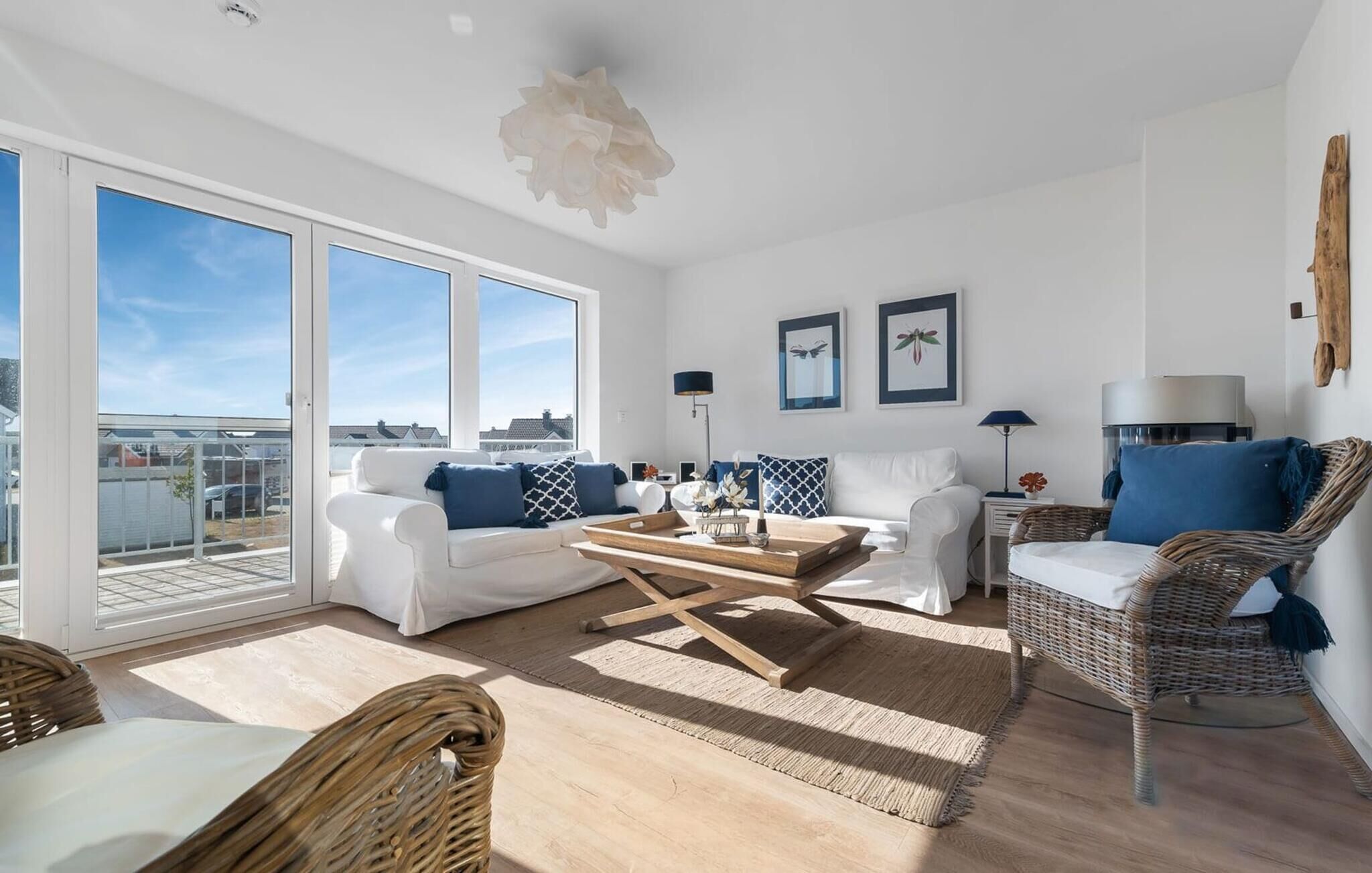 A spacious living room with a large window, white furniture, and a view of the city.