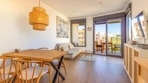 Una sala de estar moderna con una mesa de comedor de madera, sillas, un sofá y un balcón con vista a la ciudad.