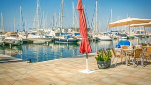 Marina con barcos amarrados, asientos exteriores y cielo despejado.