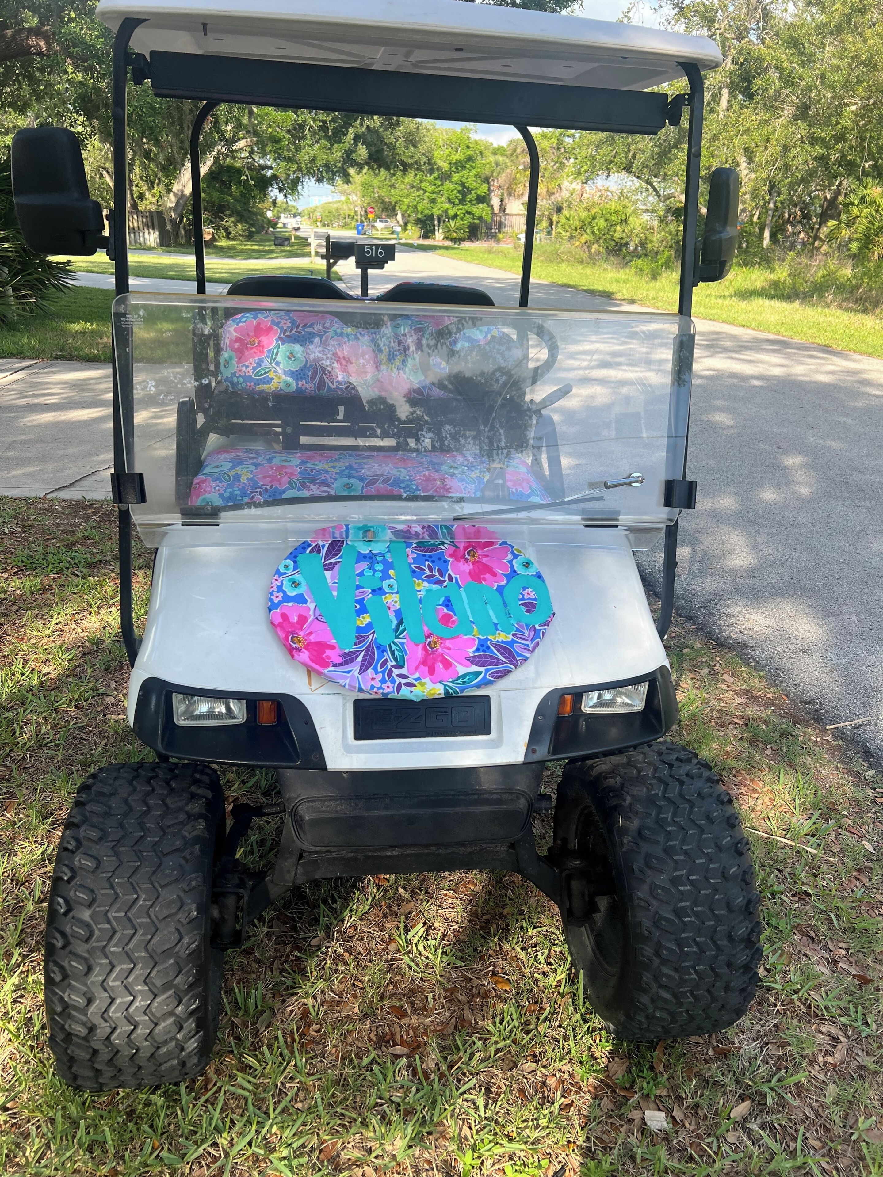 A golf cart with a floral seat cover and a license plate.