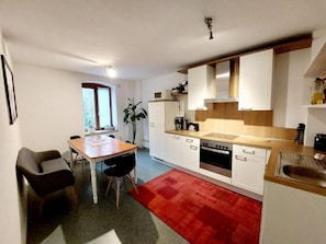 A modern kitchen with white cabinets, a wooden countertop, and a red rug.