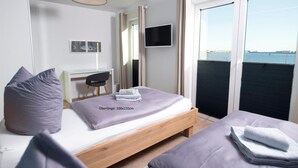 A hotel room with a bed, a desk, a chair, a TV, and a view of the sea. - Nice home in Olpenitz with sauna (Olpenitz)