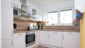 A modern kitchen with white cabinets, stainless steel appliances, and a wooden backsplash. - Nice home in Olpenitz with sauna (Olpenitz)