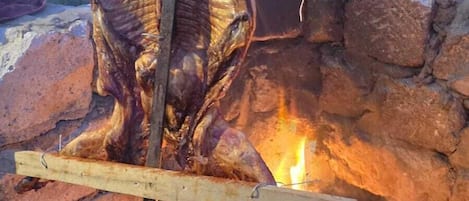 A person grilling a large animal over an open fire.