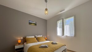 Ein Schlafzimmer mit einem Bett, zwei Nachttischlampen, einem Fenster und einem Bild an der Wand.