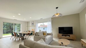 Ein modernes Wohnzimmer mit Sofa, Fernseher und Essbereich.