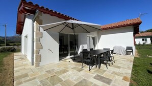 Ein überdachter Patio-Bereich mit Tisch und Stühlen, einer Schiebetür aus Glas und einem gefliesten Boden.