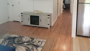 A modern living room with a flat-screen TV mounted on the wall, a built-in cabinet with a decorative shell, and a wooden floor.