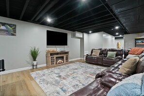 A modern living room with a fireplace, leather sofas, a flat-screen TV, and a large rug.