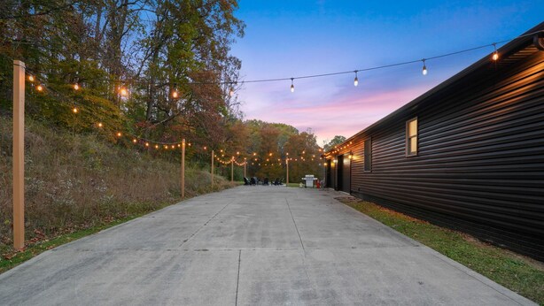 Un chemin en béton mène à un bâtiment, et des guirlandes lumineuses sont suspendues au-dessus.