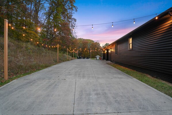 A concrete pathway leading to a building with string lights overhead.