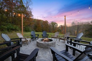 An outdoor seating area with Adirondack chairs and a fire pit.