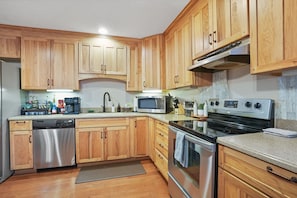 A kitchen with wooden cabinets, stainless steel appliances, a microwave, and a stove.